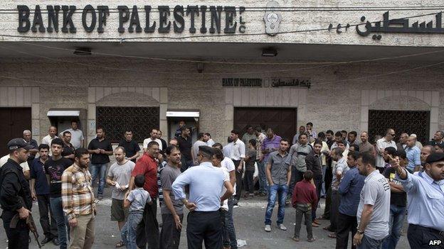 Hamas security forces stand guard as employees paid by the Palestinian Authority wait to receive their salaries outside a closed bank after a scuffle with employees appointed by Hamas since 2007, in Gaza City on June 5,