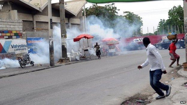 Residents flee tear gas fired by Haitian police at anti-government protesters in Port-au-Prince, Haiti, 5 June 2014