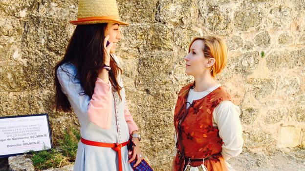 Two women dressed in medieval clothes, one of them on a mobile phone
