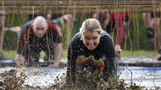 A Tough Mudder participant makes her way through electric wires