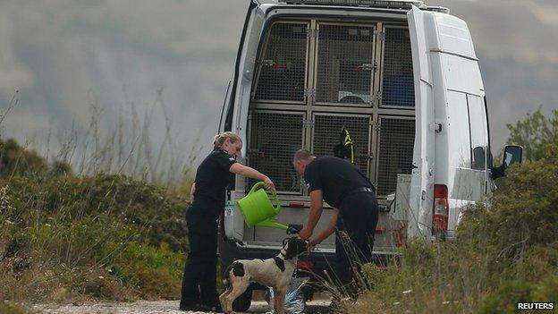 Officers pour water over the dogs to keep them cool during the search