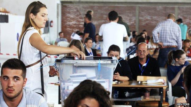 A Kosovo Albanian woman places her ballot paper into a voting box at the polling station in the capital city Pristina June 8