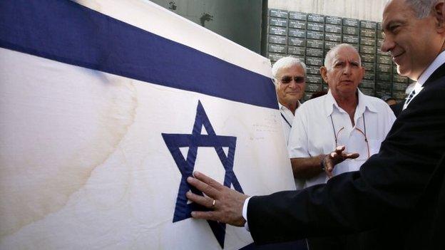 Israeli Prime Minister Benjamin Netanyahu touches the original flag Israeli paratroopers waved at the Western Wall in the 1967 Six Day War prior to a special Jerusalem Day Cabinet Meeting at Ammunition Hill on May 28