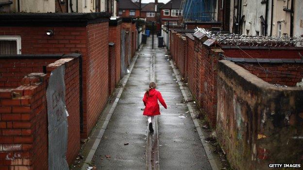 Child runs through back lane behind houses