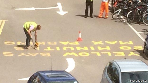 Workman painting road marking at railway station in Cambridge