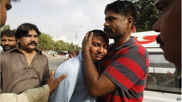 People comfort a relative of a killed airport worker, Karachi (9 June 2014)