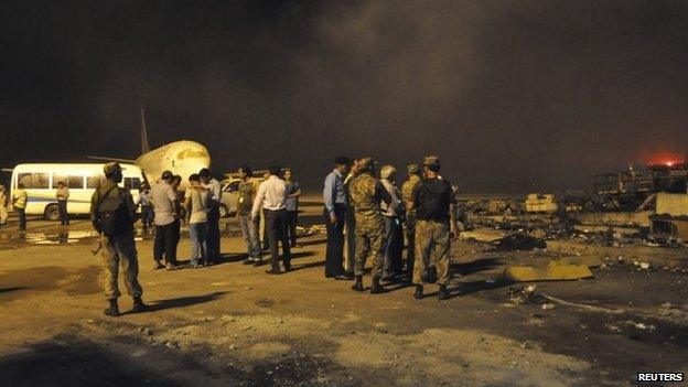 Smoke bellows as security officials and airport staff visit the site damaged by Sunday's Taliban attack on Jinnah International Airport in Karachi, 9 June 2014