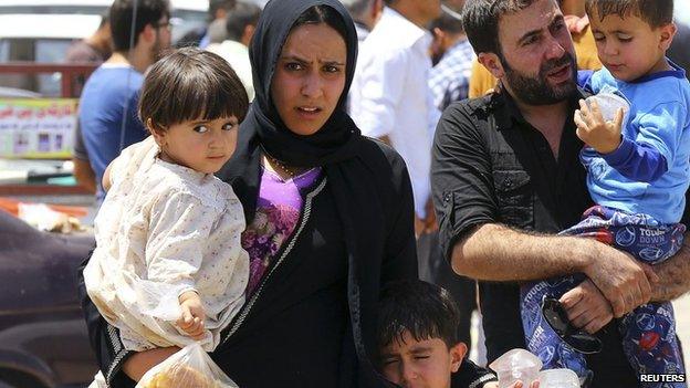 A family fleeing the violence in the Iraqi city of Mosul waits at a checkpoint near Erbil, in Iraq's Kurdistan region, 10 June 2014