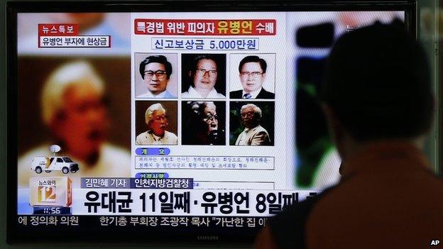 A man watches the TV news program on the reward poster of Yoo Byung-eun at the Seoul Train Station in Seoul, South Korea, on Friday, 23 May, 2014