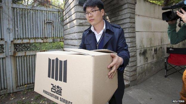 An official from the Incheon District Prosecutors" office carries a box during a raid of the home of Yoo Byung-un, in Seoul on 23 April, 2014