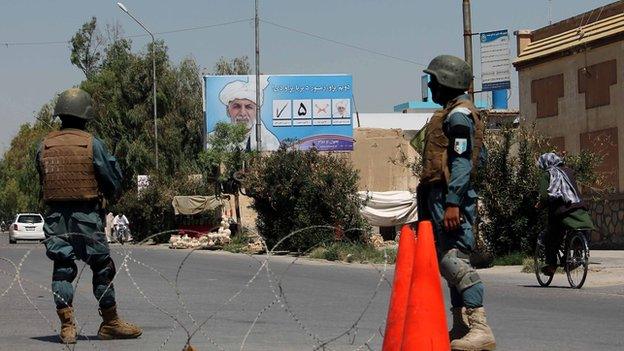 A campaign poster of Ashraf Ghani overlooks a security checkpoint in Kandahar