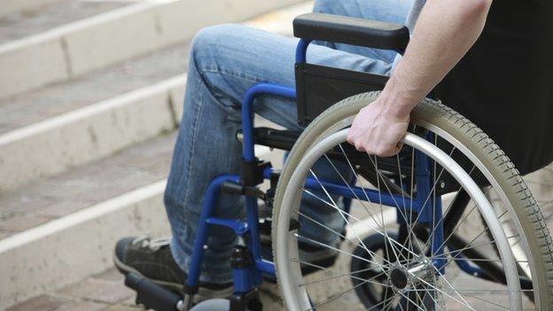 A man in a wheelchair at the bottom of a flight of stairs