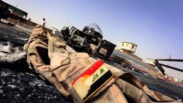 The jacket of an Iraqi army uniform lies on the ground in front of a burnt out Iraqi army vehicle east of the northern city of Mosul, on 11 June 2014,