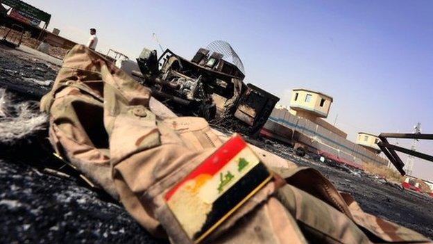 The jacket of an Iraqi army uniform lies on the ground in front of a burnt out Iraqi army vehicle east of the northern city of Mosul, on 11 June 2014,