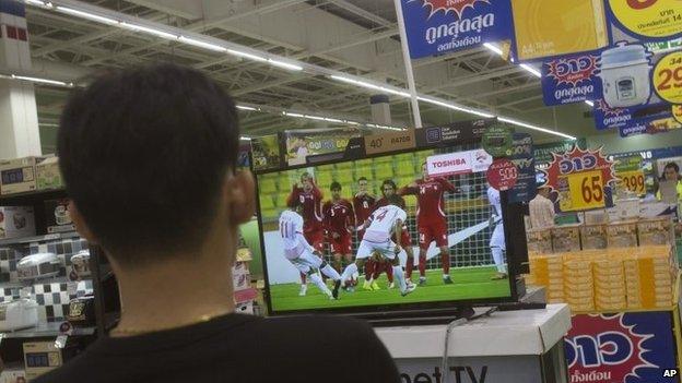 A Thai shopper watches a soccer match on a flat-panel television at a shopping mall in Bangkok, Thailand Wednesday, June 11