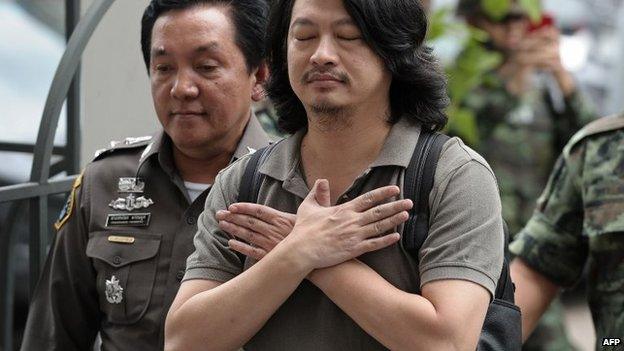 Thai anti-coup activist Sombat Boonngamanong (C) gestures as he arrives escorted by police and soldiers at a military court in Bangkok on June 12