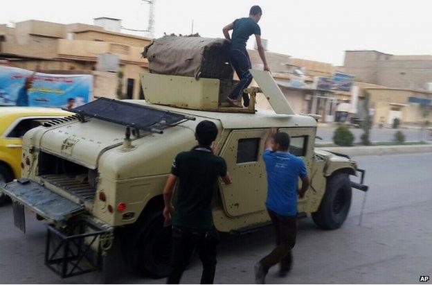 Teenagers ride a captured Iraqi army vehicle in Tikrit, 11 June