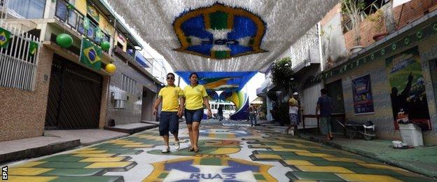 A Brazilian couple walks on a painted and decorated street to celebrate the 2014 World Cup at a residential area in Manaus