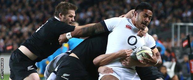 Richie McCaw tries to pull Manu Tuilagi back as two of more New Zealanders struggle to bring the England centre to ground