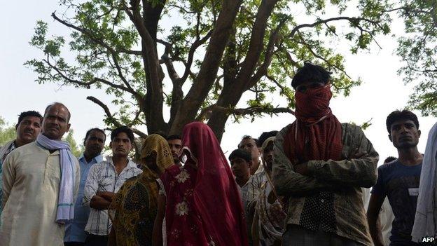 In this May 31, 2014, photo mothers of gang-rape victims (C, shawls covering their faces) and villagers stand in front of the mango tree where the girls were hanged in Katra Shahadatgunj in Badaun district