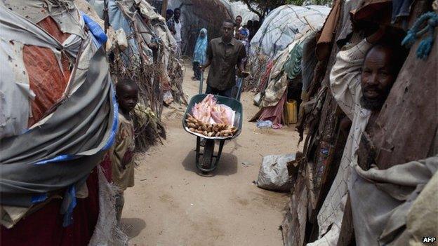 A man sells loafs of bread from a wheelbarrow in a displacement camp in Mogadishu