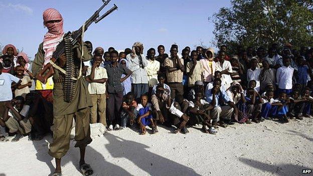 A hooded Somali Islamist fighter stands guard over a crowd that gathered to watch the public flogging of teenaged boys convicted of raping a minor in Mogadishu, Somalia - 2009