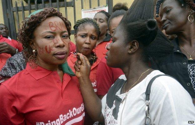 A woman writes the slogan "Bring Back Our Girls" on the face of another as they prepare to march in Lagos, Nigeria, on 29 May 2014