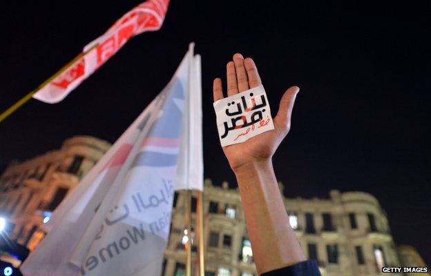 A woman holds her hand up at a demonstration against sexual assault in Egypt