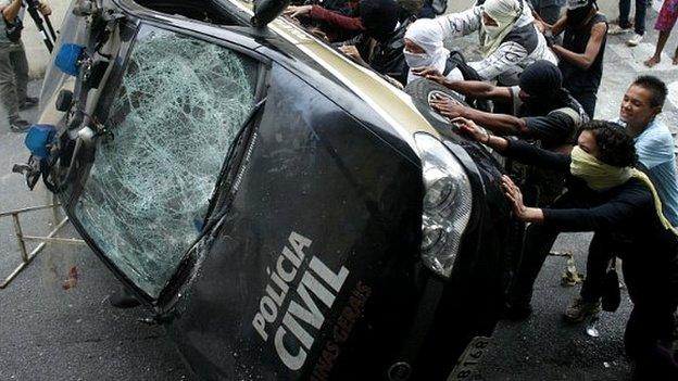 Demonstrators push over a police car during a protest in Belo Horizonte, Brazil - 12 June, 2014