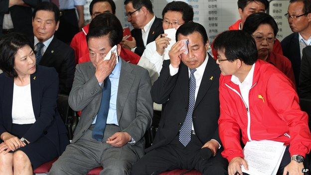 Lee Wan-goo, Chairman of the Party's campaign, wipes the sweat off his face as members watch a television program broadcasting the election exit polls in Seoul, South Korea, on Wednesday, 4 June, 2014