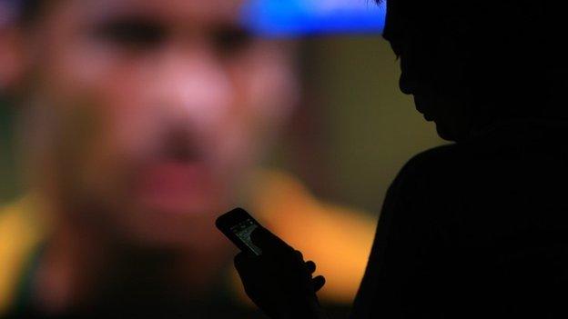 A football fan checks his phone as he watches the opening football match between Brazil and Croatia of the 2014 FIFA World Cup in a stadium in Changsha, central China"s Hunan province in the early morning of June 13