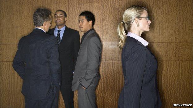 Three men talk while a woman passes by