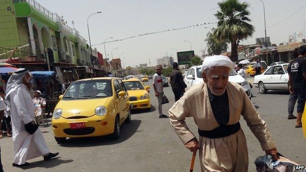 Iraqis walk on a street in the northern city of Kirkuk on 13 June 2014