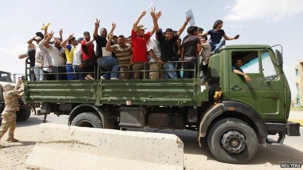 Volunteers who have joined the Iraqi Army to fight against the predominantly Sunni militants, who have taken over Mosul and other Northern provinces, gesture from an army truck in Baghdad 13 June 2014