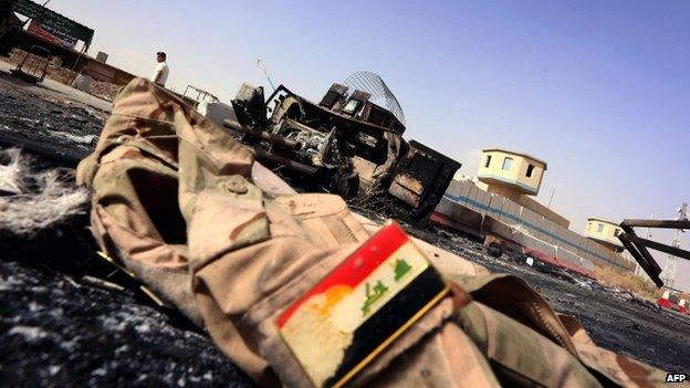 An Iraqi army jacket lies on the ground in front of the remains of a burnt-out military vehicle close to the Kukjali Iraqi Army checkpoint, some 10km (6 miles) east of the northern city of Mosul (June 2014)