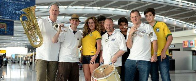 The official England band brought the party spirit to the airport on their way to Brazil