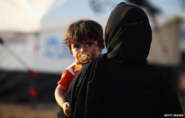 Woman holds child at displaced persons' camp, Kalak, Iraq (14 June)