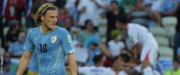 Diego Forlan looks pensive as Costa Rica celebrate scoring