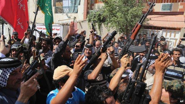 Iraqi Shiite tribal fighters raise their weapons in Baghdad's Sadr City,