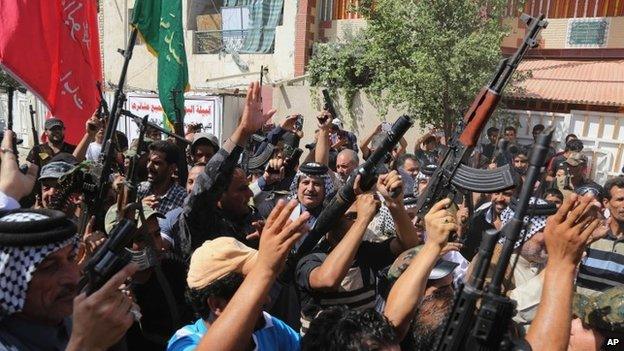 Iraqi Shia fighters raise their weapons and chant slogans in Baghdad's Sadr City, June 14, 2014