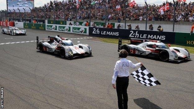 Audi team crosses the finish line to take the chequered flag in its 379th and last lap to win the 82nd Le Mans 24 Hour Race