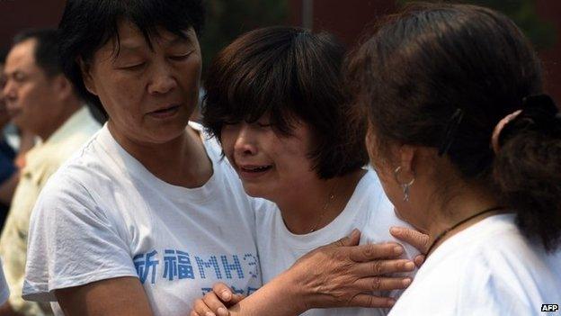 Relatives of passengers on missing Malaysia Airlines flight MH370 cry as they gather at the Lama Temple in Beijing on June 15