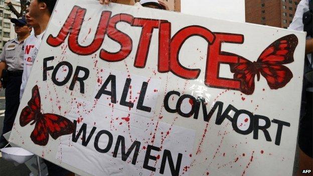 A demonstrator displays a placard as the group demands an apology from Japan over the comfort women issue during a rally in front the Japan Interchange Association in Taipei on 14 August, 2013