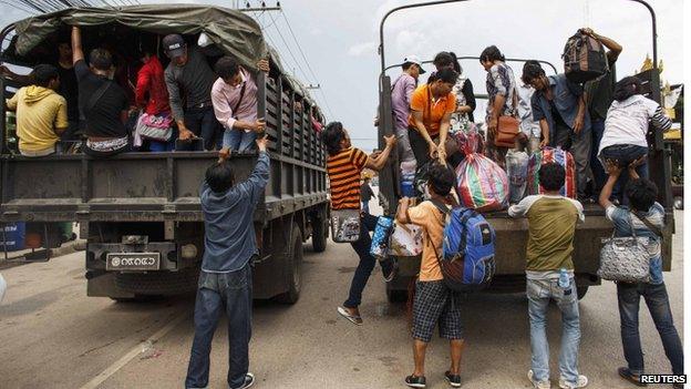 Cambodian workers ride on military trucks as they prepare to cross the Thai-Cambodia border at Aranyaprathet on 15 June.