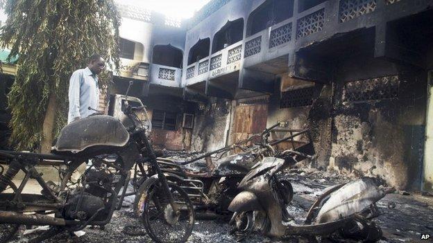 A man observes the remains of destroyed vehicles and buildings in the town of Mpeketoni in Kenya on 16 June 2014