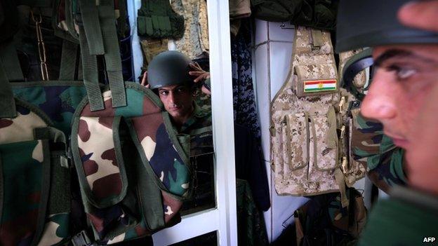 An Iraqi man tries on a military uniform in a shop in Irbil (16 June 2014)