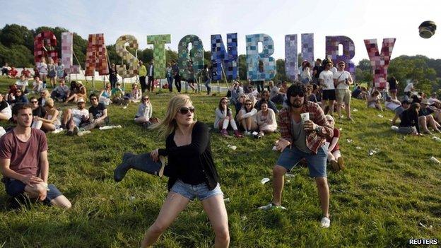 Festival-goers play a game, batting a beer can with a Wellington boot, on the first day of the Glastonbury music festival at Worthy Farm in Somerset, in this June 27, 2013