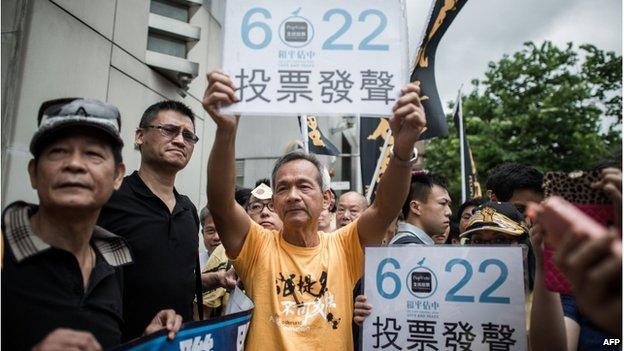 Demonstrators supporting the Occupy Central movement display placards asking residents to cast ballots for the 22 June during a protest outside Beijing's representative office in Hong Kong, on 11 June.