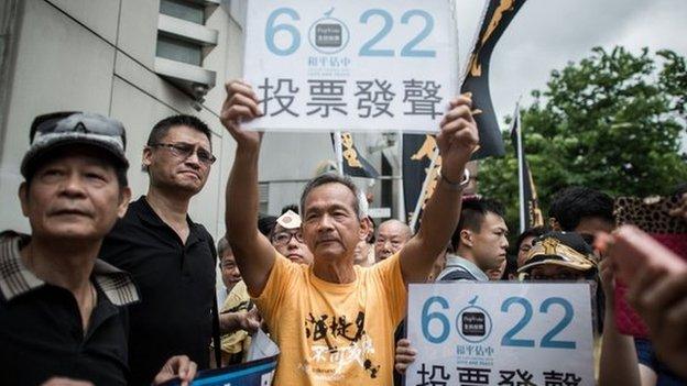 Demonstrators supporting the Occupy Central movement display placards asking residents to cast ballots for the 22 June during a protest outside Beijing's representative office in Hong Kong, on 11 June.