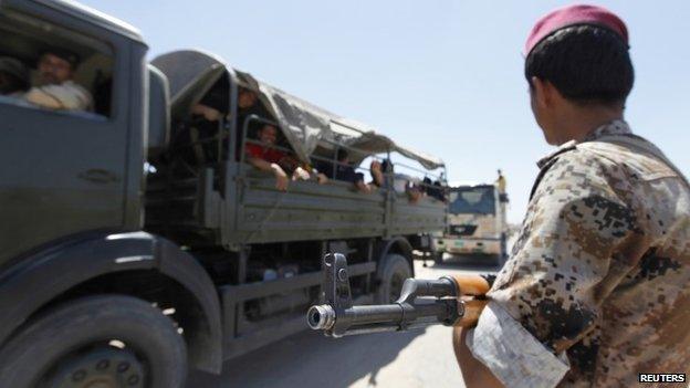 A member of Iraqi security forces stands guard near volunteers in Baghdad, June 17, 2014